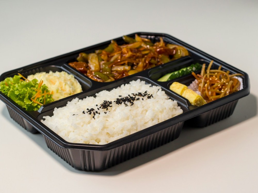 검은 도시락 용기에 흰밥과 반찬이 칸별로 담긴 모습
