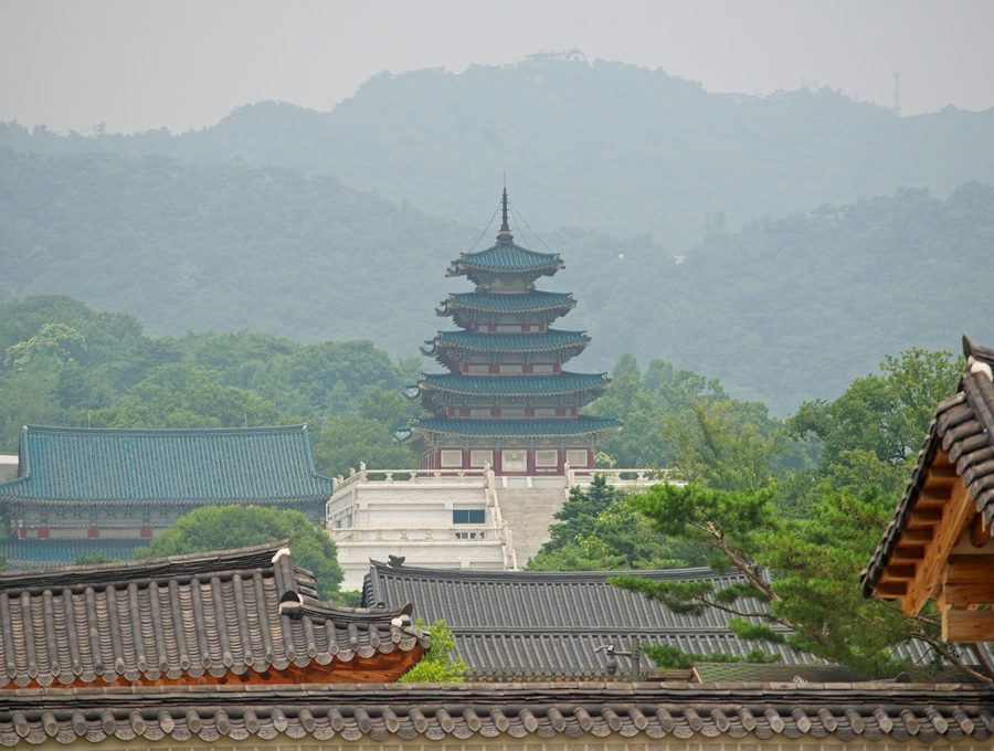 안개 낀 산을 배경으로 단청이 살아 있는 한옥 누각의 처마 곡선